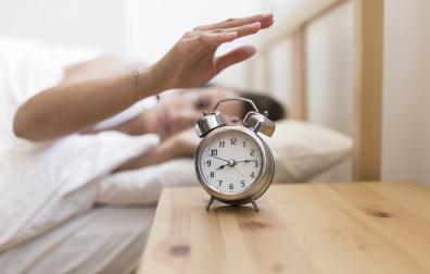 Una mujer apaga el despertador por la mañana
