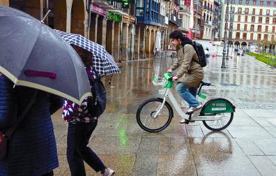 Un usuario del sistema de alquiler de bici eléctrica, ayer bajo la lluvia.