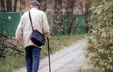 Un anciano anda apoyándose en un bastón
