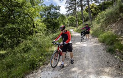 Dos cicloturistas atraviesan, pie en tierra, un tramo de la Vía Verde del Plazaola.