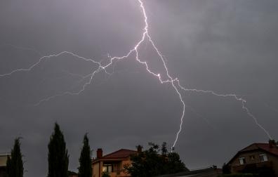 Un rayo que cae cerca de unas casas en una tormenta eléctrica