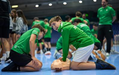 Jóvenes integrantes de la sección de balonmano de Anaitasuna, practicandio maniobras de reanimación (RCP) con un muñeco en la sesión formativa