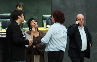 Pablo Azcona (Geroa Bai), Laura Aznal (EH Bildu) y Ainhoa Unzu (PSN) hablan en el atrio del Parlamento en un día en el que deben cerrar el acuerdo con las medidas fiscales para 2026. A la derecha, el consejero de Educación, Carlos Gimeno