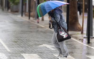 Una mujer se protege del viento con su paraguas con la llegada de la borrasca Claudia