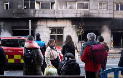 Vecinos y curiosos observan los efectos del fuego en el edificio tras el incendio de un bazar en la Rochapea
