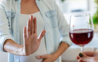 Una mujer rechaza una copa de vino