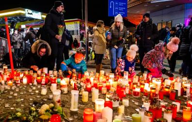 Varias personas colocan velas en memoria de los fallecidos en Suiza
