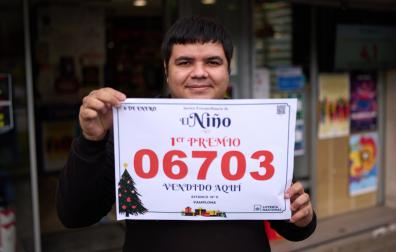 Andrey Mendes muestra con orgullo el cartel con el número agraciado delante de la administración de loterías en el número 52 de la avenida de Barañáin