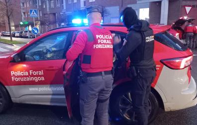 Un agente de la Policçia Foral y otro de la Policía Nacional introducen al agresor en un coche patrulla