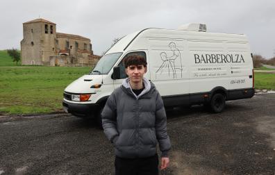 Ion Olza posa delante de la furgoneta ya rotulada y convertida en barbería móvil. Detrás la iglesia de su pueblo, Asiáin
