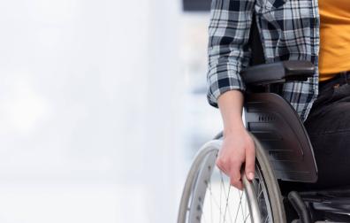 Una persona con discapacidad se apoya en su silla de ruedas