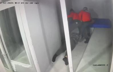 Un fotograma de la grabación de calabozos: dos de los agentes acusados (a la izquierda el que propinó los golpes), tras tirar al detenido al suelo para engrilletarlo