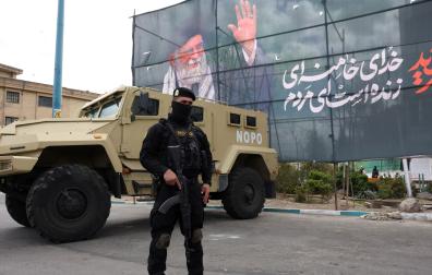 Un miembro de las fuerzas de seguridad iraníes monta guardia junto a una pancarta en honor al exlíder supremo iraní Ali Jamenei, en Teherán
