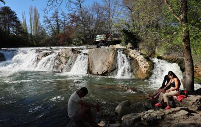 Tres personas se refrescan en la presa de Huarte e estos días de calor.