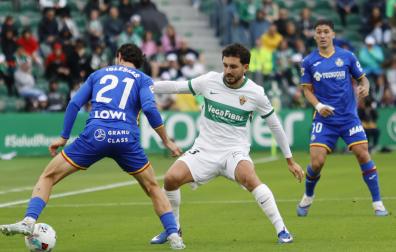 El defensa del Elche Víctor Chust disputa un balón con el defensa del Getafe Juan Iglesias  durante el encuentro de la jornada 37