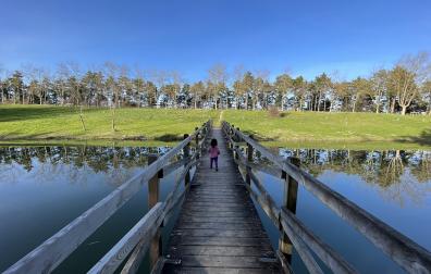 Una niña atraviesa el puente de madera de la balsa de Ardoi