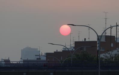 Vista del amanecer desde Plaza Elíptica con un manto de ceniza sobre Madrid este sábado debido a los incendios forestales que asolan la comunidad
