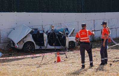 Dos agentes de Policía Foral, junto al vehículo accidentado en el que viajaban dos personas que han perdido la vida este jueves en Beriain