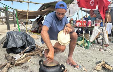 Varios inmigrantes se preparan la comida este miércoles en la playa del Trampolín