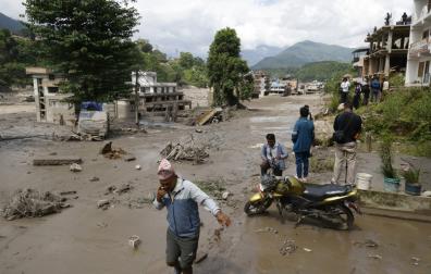 Varias personas caminan por las calles inundadas en Trishuli Bazar, en el distrito de Nuwakot