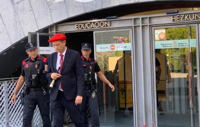 Ricardo Oficialdegui, con vestido de gaitero y con el instrumento en la mano, abandona la sede de Educación acompañado de dos agentes de la Policía Foral
