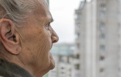 An elderly woman looking out the window