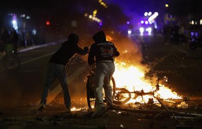 Dos estudiantes alimentan una hoguera durante las protestas de la pasada noche en Barcelona