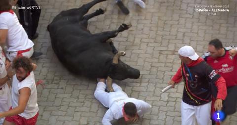 Un mozo, atrapado bajo un toro caído antes de la entrada al callejón