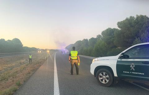 GCivil Una patrulla de la Guardia Civil regula el tráfico con el coche incendiado en segundo plano