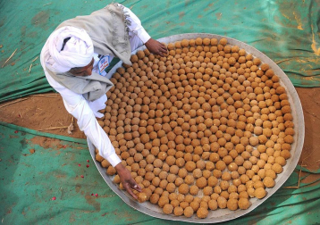 Trabajadores disponen 'laddus' (dulces) en una cocina en Ahmedabad, una ciudad al oeste de la India. Más de 300.000 'laddus' fueron fabricados para el banquete de una ceremonia religiosa organizada para el Brahmins, la casta superior de hindús.