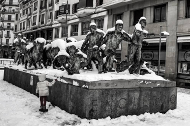 Monumento al encierro, nevado, mientras una niña lo observa
