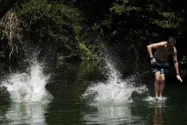 Varias personas se alivian del calor en el pantano de Alloz y en el río Arga a su paso por Irotz.