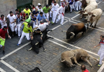 Momentos de tensión cuando el morlaco jabonero de la ganadería de Núñez del Cuvillo perdió pie en la calle Estafeta y cayó al suelo, rodeado de mozos.