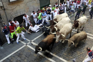 Momentos de tensión cuando el morlaco jabonero de la ganadería de Núñez del Cuvillo perdió pie en la calle Estafeta y cayó al suelo, rodeado de mozos.