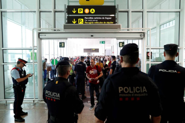 Agentes de los Mossos d'Esquadra y de la Policía Nacional controlan el acceso de personas a la terminal 1 del Aeropuerto de El Prat.