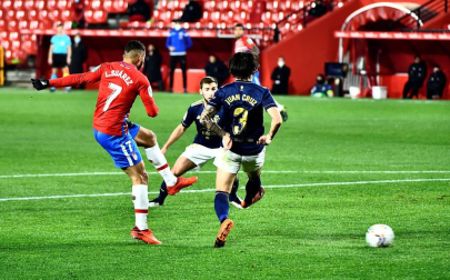 El delantero colombiano del Granada Luis Suárez golpea el balón ante dos rivales de Osasuna,