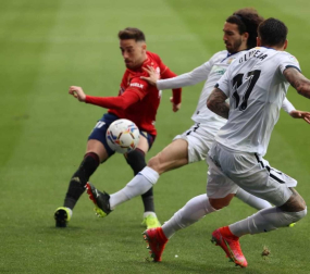 Kike Barja golpea al balón ante dos jugadores del Getafe.