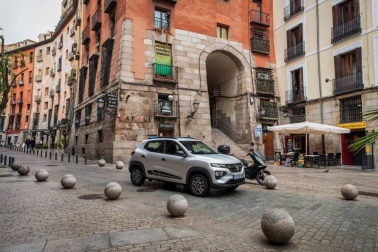Así es el Dacia Spring, el rey eléctrico de la ciudad. Con solo 3,7 metros de largo, es el vehículo más recomendado para rodar sin emisiones por la ciudad. Su autonomía urbana de 305 kilómetros tienen la culpa, además de su precio, de solo 9.950 euros con el Plan MOVES III incluido. El Seat Mii es su rival más directo. Su tamaño es diminuto, pero destaca su estética SUV de bolsillo.
Como se aprecia en las imágenes, luce pasos de ruedas más anchos, barras de techo, bajos de carrocería delanteros reforzados, protección trasera y distancia al suelo sobreelevada (151 mm en vacío). Tras el logotipo del frontal, con una calandra cerrada al tratarse de un coche eléctrico, se ubica disimuladamente la boca de carga. Las luces LED más afiladas remarcan la línea horizontal de la mirada del Spring. Los embellecedores de este vehículo imitan la estética de las llantas de aleación. Esta apariencia es posible gracias al sistema Flexwheel: las llantas de chapa son abiertas.
Su motor ofrece un potencia de 44 CV, suficiente para rodar por ciudad, dado su bajo peso, de menos de una tonelada. Como curiosidad, no dispone de una palanca de cambios al uso. Ofrece ahora un selector de marcha giratorio con una rueda cromada muy sencilla de utilizar, con 3 posiciones: D (drive), N (neutral) y R (retroceso). A bordo de Dacia Spring se pueden instalar cuatro adultos cómodamente y cuenta con un maletero generoso de casi 300 litros de capacidad.