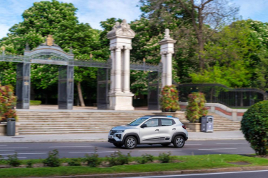 Así es el Dacia Spring, el rey eléctrico de la ciudad. Con solo 3,7 metros de largo, es el vehículo más recomendado para rodar sin emisiones por la ciudad. Su autonomía urbana de 305 kilómetros tienen la culpa, además de su precio, de solo 9.950 euros con el Plan MOVES III incluido. El Seat Mii es su rival más directo. Su tamaño es diminuto, pero destaca su estética SUV de bolsillo.
Como se aprecia en las imágenes, luce pasos de ruedas más anchos, barras de techo, bajos de carrocería delanteros reforzados, protección trasera y distancia al suelo sobreelevada (151 mm en vacío). Tras el logotipo del frontal, con una calandra cerrada al tratarse de un coche eléctrico, se ubica disimuladamente la boca de carga. Las luces LED más afiladas remarcan la línea horizontal de la mirada del Spring. Los embellecedores de este vehículo imitan la estética de las llantas de aleación. Esta apariencia es posible gracias al sistema Flexwheel: las llantas de chapa son abiertas.
Su motor ofrece un potencia de 44 CV, suficiente para rodar por ciudad, dado su bajo peso, de menos de una tonelada. Como curiosidad, no dispone de una palanca de cambios al uso. Ofrece ahora un selector de marcha giratorio con una rueda cromada muy sencilla de utilizar, con 3 posiciones: D (drive), N (neutral) y R (retroceso). A bordo de Dacia Spring se pueden instalar cuatro adultos cómodamente y cuenta con un maletero generoso de casi 300 litros de capacidad.