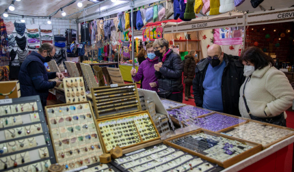 Varias personas observan los productos que ofrece uno de los puestos en la feria navideña de la Plaza de Toros