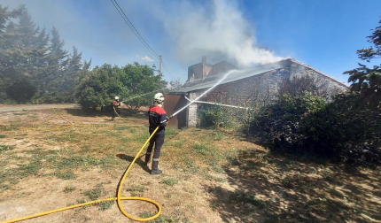 Los bomberos tratan de apagar las llamas de una de las viviendas ardiendo en Arguiñáriz