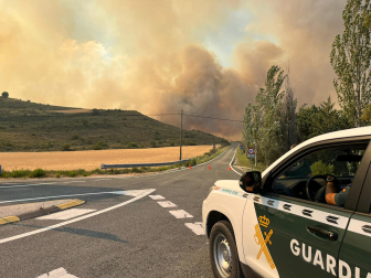 Un coche de la Guardia Civil corta la carretera ante el avance del incendio en Lerga.