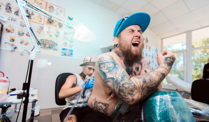 Un tatuador realiza un tatuaje en la espalda de un cliente