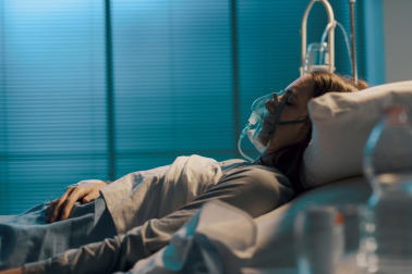Una mujer, con una mascarilla de oxígeno, en un hospital