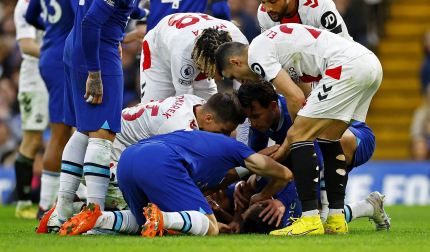 César Azpilicueta tendido sobre el césped tras recibir el impacto, recibe la asistencia de sus compañeros.