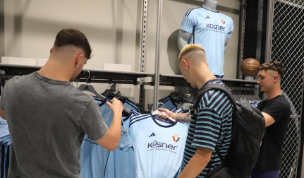 Varios jóvenes, con las nuevas camisetas en la tienda de Osasuna