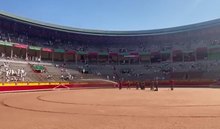 Los areneros riegan la arena de la plaza de toros antes de la corrida del 9 de julio