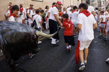 Un grupo de niños corre por delante de un toro de cartón en la Cuesta de Santo Domingo, Pamplona, durante el encierro 'txiki' que se ha celebrado este martes a mediodía y en el que, al tratar de ser lo más real posible al encierro grande, también se canta al santo y se disparan cohetes desde el corral para avisar de la salida de la manada compuesta por seis toros y tres bueyes sobre ruedas.