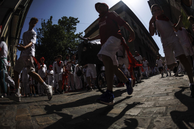 Un grupo de niños corre por delante de un toro de cartón en la Cuesta de Santo Domingo, Pamplona, durante el encierro 'txiki' que se ha celebrado este martes a mediodía y en el que, al tratar de ser lo más real posible al encierro grande, también se canta al santo y se disparan cohetes desde el corral para avisar de la salida de la manada compuesta por seis toros y tres bueyes sobre ruedas.