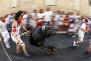 Un grupo de niños corre por delante de un toro de cartón en la Cuesta de Santo Domingo, Pamplona, durante el encierro 'txiki' que se ha celebrado este martes a mediodía y en el que, al tratar de ser lo más real posible al encierro grande, también se canta al santo y se disparan cohetes desde el corral para avisar de la salida de la manada compuesta por seis toros y tres bueyes sobre ruedas.